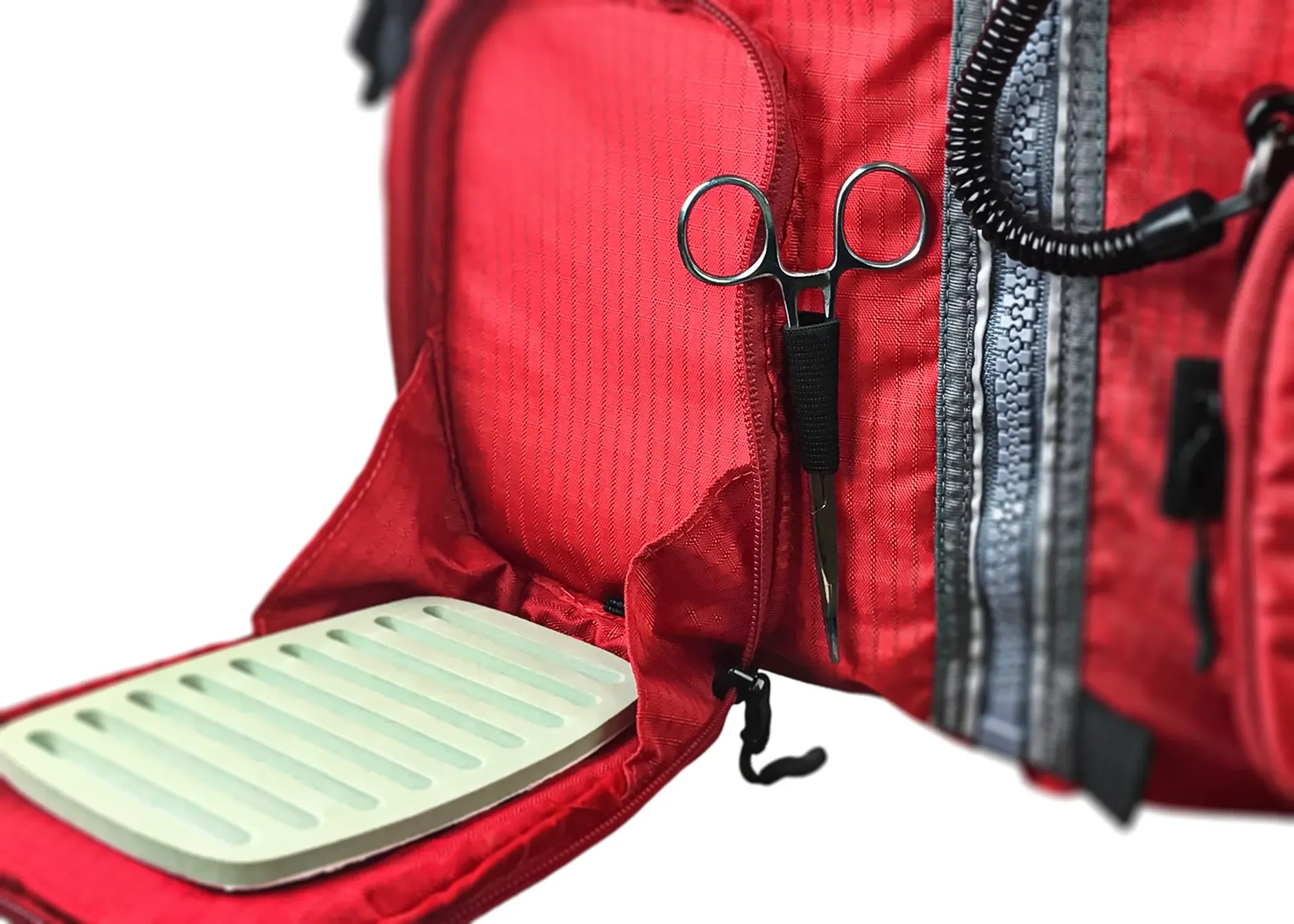 Close-up of Stohlquist red kayaking life jacket with zippered pocket, tool holder, and fishing accessory panel.