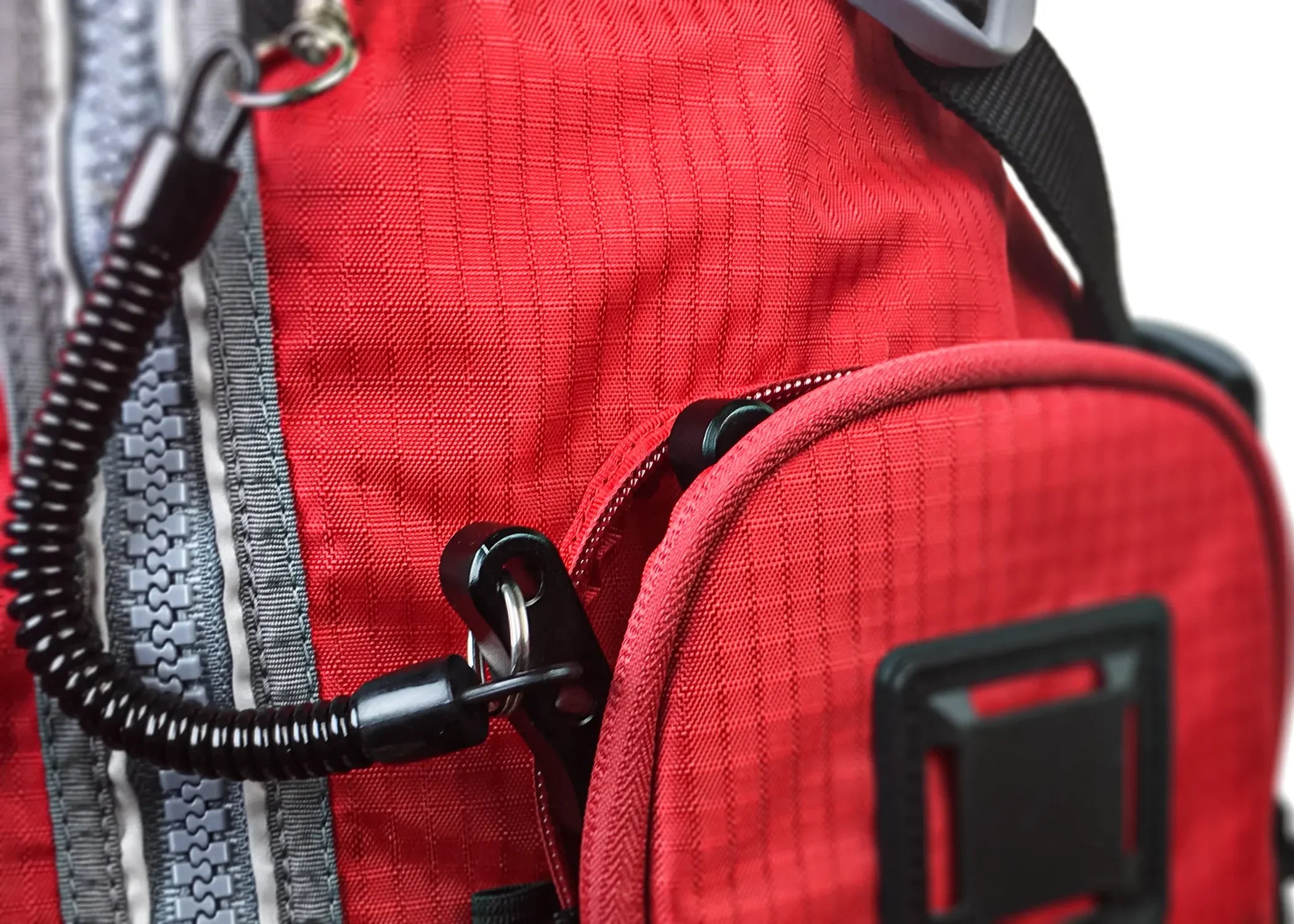 Close-up of Stohlquist red kayaking life jacket with secure zip pocket and coiled safety tether
